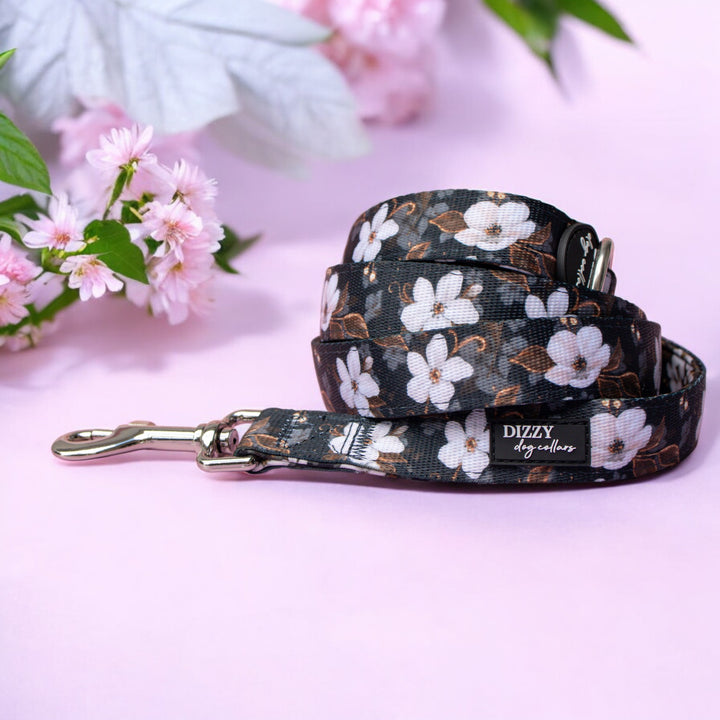 Floral-patterned dog collar and leash on a pink background with flowers.