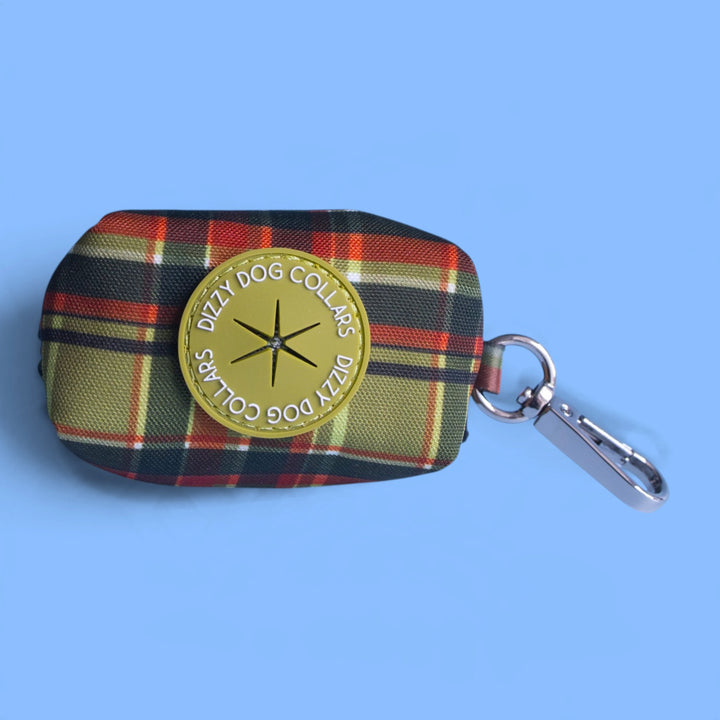A small plaid fabric pouch with a round yellow brand patch reading 'Dizzy Dog Collars' and a silver metal clasp, photographed on a light blue background.